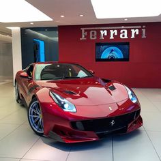 a red sports car parked in front of a ferrari sign