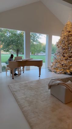 a person sitting at a piano in front of a christmas tree with lights on it