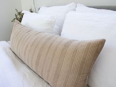 a close up of a pillow on a bed with white sheets and pillows in the background