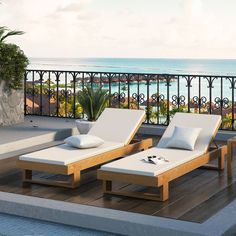 two lounge chairs sitting on top of a wooden deck next to an ocean and palm tree