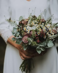 a woman holding a bouquet of flowers in her hands