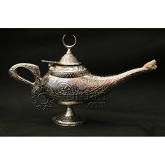 an ornate silver teapot on a black background