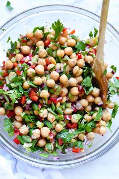 a glass bowl filled with chickpeas, lettuce and red onion salad