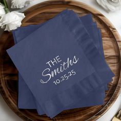 three blue napkins with the words the snutches printed on them sitting on a wooden plate