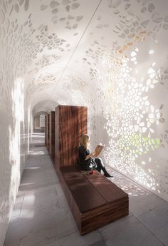 a woman is sitting on a bench in the middle of a room with white walls