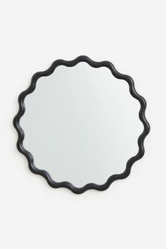 an oval black mirror on a white wall