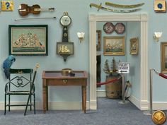 a room filled with lots of framed pictures and paintings on the wall next to a desk