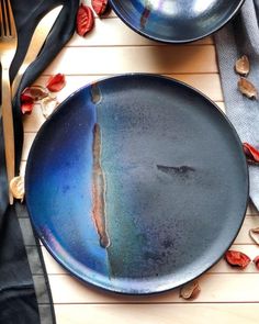 two blue plates sitting on top of a wooden table next to forks and spoons