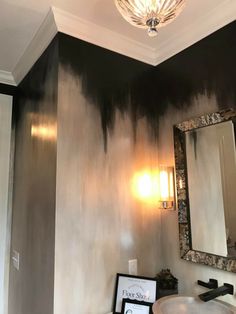 a bathroom with black and white paint on the wall next to a mirror, sink and light fixture