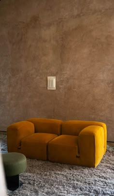 an orange couch sitting on top of a carpet covered floor