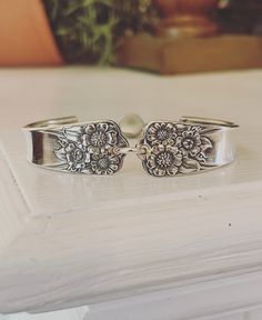 two silver bracelets sitting on top of a white table