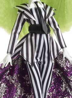 a doll dressed in black and white striped clothing with purple flowers on the bottom half