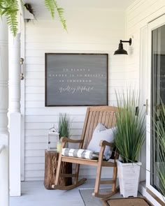 a porch with a rocking chair, potted plants and a chalkboard on the wall