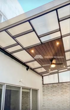 an outdoor covered patio with sliding glass doors and lights on the ceiling, in front of a white brick building