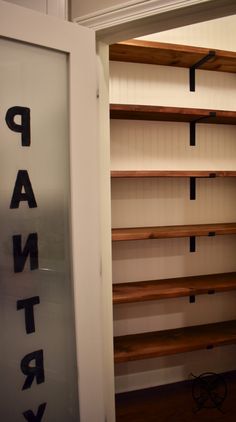 an empty pantry with wooden shelves and black letters