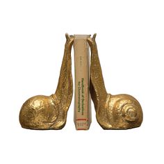 two golden snail bookends sitting next to each other