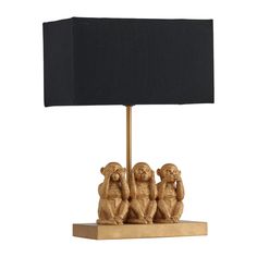 a table lamp with three monkeys on it and a black shade over the light fixture