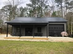 a black garage with two doors and windows in front of some trees on the other side