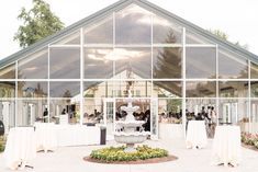 an outdoor venue with tables and chairs set up for a wedding reception in front of a large glass building