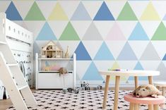 a child's room with colorful triangles painted on the wall and a play table