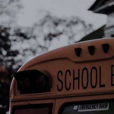 the back end of a school bus parked in front of a building with trees behind it