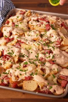 a pan filled with potatoes covered in gravy and garnished with green onions