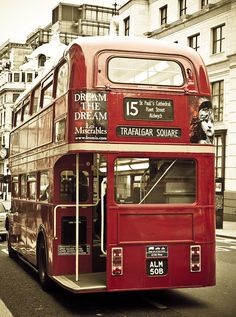 a red double decker bus driving down the street