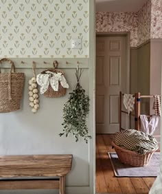 a bench and wall hangings in a room next to a door with flowers on it