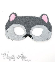 a black and grey mask with pink ears on it's face is shown in the shape of a cat