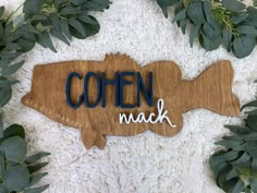 a wooden sign that says coen nack on it next to some green leaves