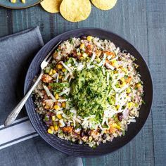 a bowl filled with rice and vegetables next to tortilla chips