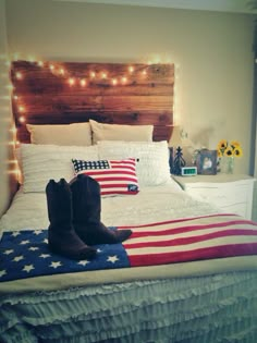 a pair of cowboy boots sitting on top of a bed with an american flag blanket