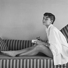 a black and white photo of a woman sitting on a couch with her legs crossed