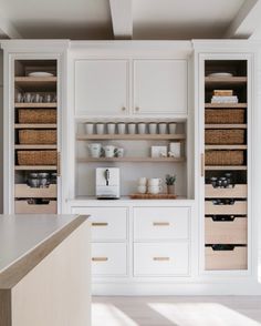 a kitchen with white cabinets and wooden drawers