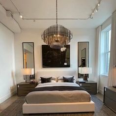 a bedroom with a large bed and chandelier hanging from the ceiling