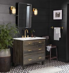 a bathroom with black walls and white flooring has a sink, mirror, and potted plant