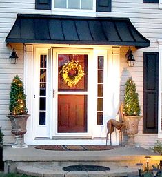 the front door is decorated with wreaths and potted plants