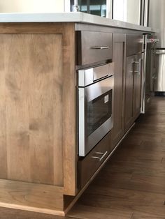 a kitchen with an island and stainless steel appliances in the center, along with hardwood flooring