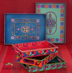 three colorful boxes with designs on them sitting in front of a red wall and floor