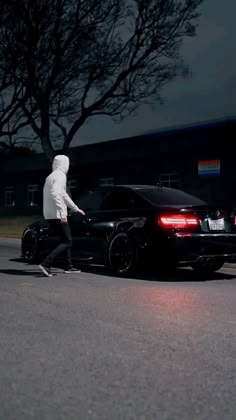 a person riding a skateboard next to a car on a street at night time