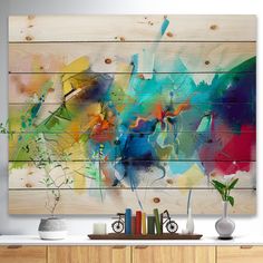 an abstract painting on wooden planks in a living room with vases and books