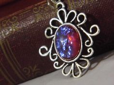 a close up of a pendant on a book with a red and blue stone in the center