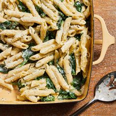 pasta with spinach and cheese in a casserole dish on a wooden table