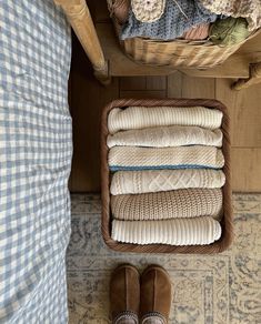 a basket filled with blankets and slippers next to a bed