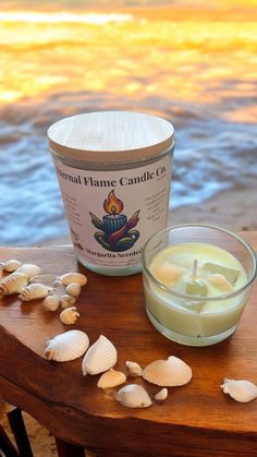 a candle sitting on top of a wooden table next to some sea shells and water