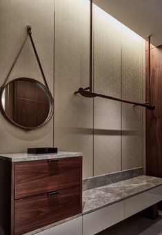 a bathroom with marble counter tops and wooden accents on the walls, along with a round mirror