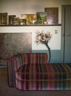 a colorful couch sitting in front of a wall with pictures on the wall above it