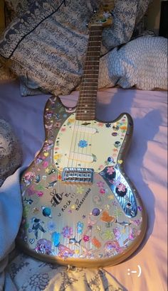 an electric guitar covered in stickers on a bed