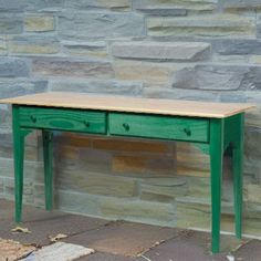 a green table sitting in front of a stone wall