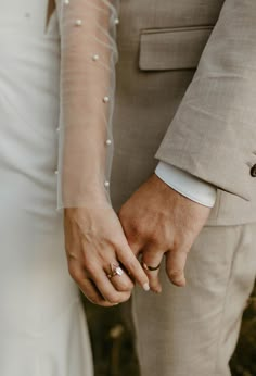 a close up of two people holding hands and wearing wedding rings with one another's hand